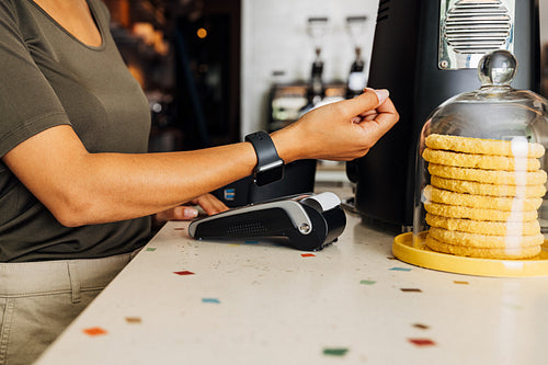 Mid section of unrecognizable customer paying contactless with her smart watch