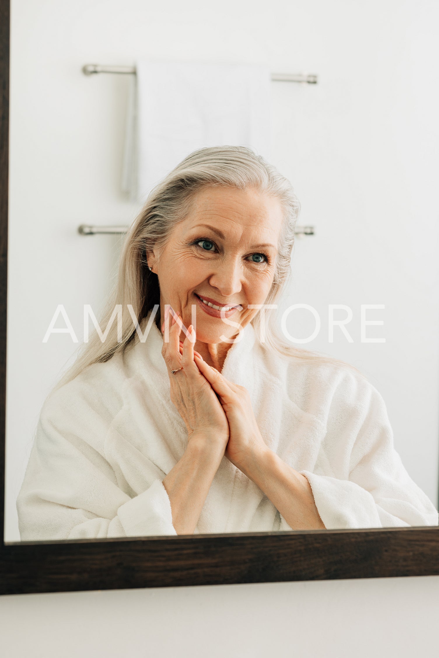 Smiling senior woman looking at her reflection in bathroom mirror