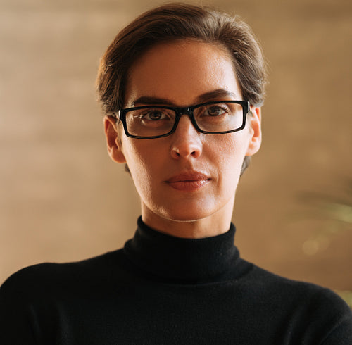 Close-up portrait of a confident businesswoman with short hair wearing eyeglasses looking straight into a camera