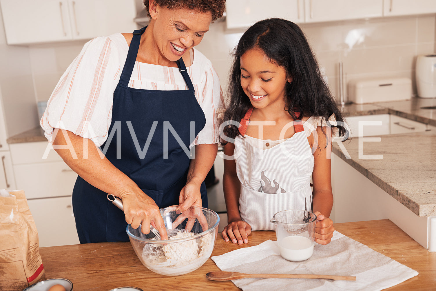 Grandmother mixing dough in a bowl while granddaughter watching