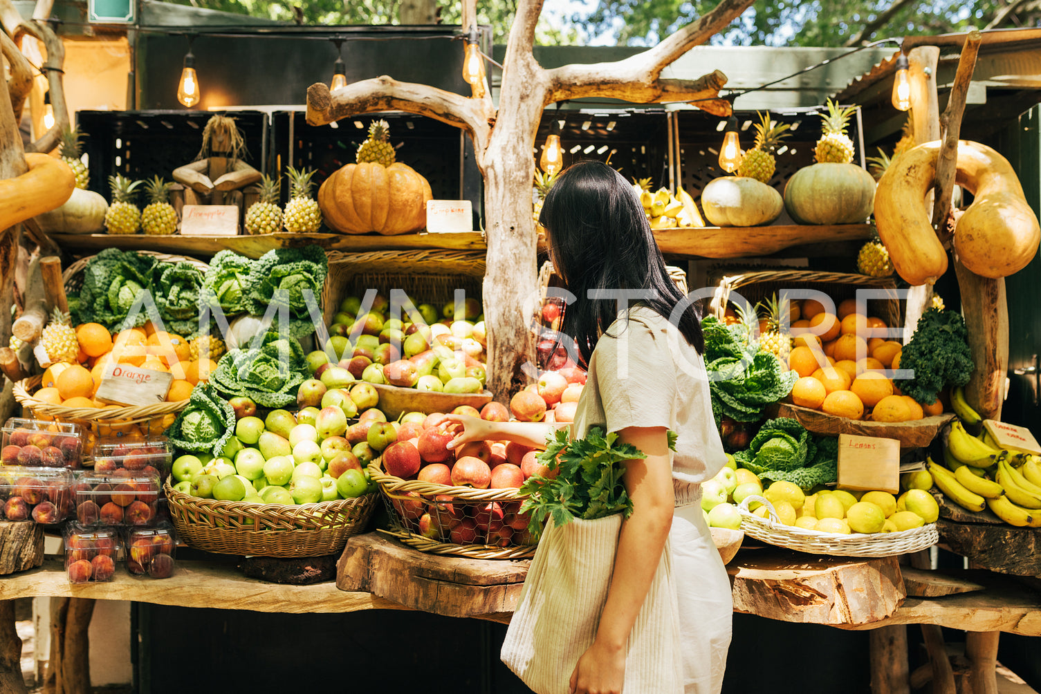 Side view of a young woman with a bag looking at vegetables and fruits at a local outdoor market.