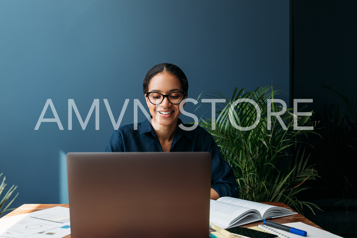 Cheerful woman in eyeglasses at the table working on laptop at home