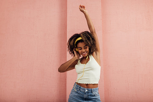 Smiling woman raising hand up while listening to music and danci