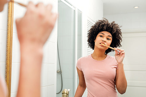 Reflection of a young woman in mirror brushing teeth