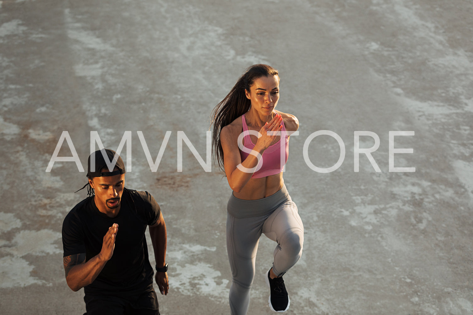 High angle of two athletes running together on the roof at sunset