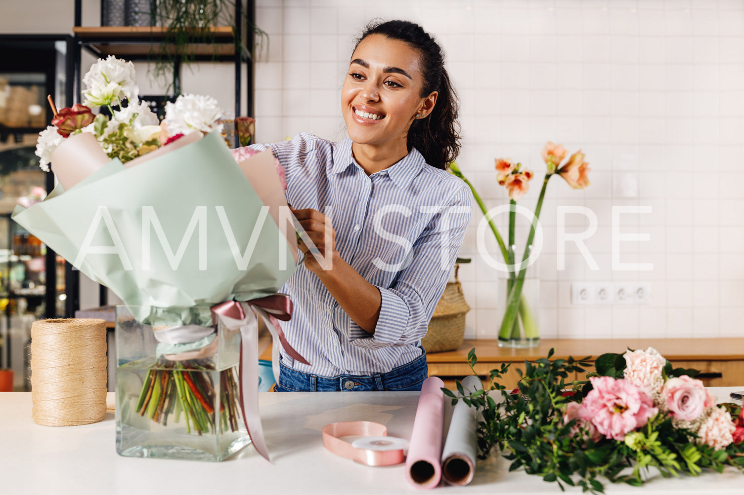 Young florist preparing a bouquet for sale. Smiling woman working in her small flower shop.	