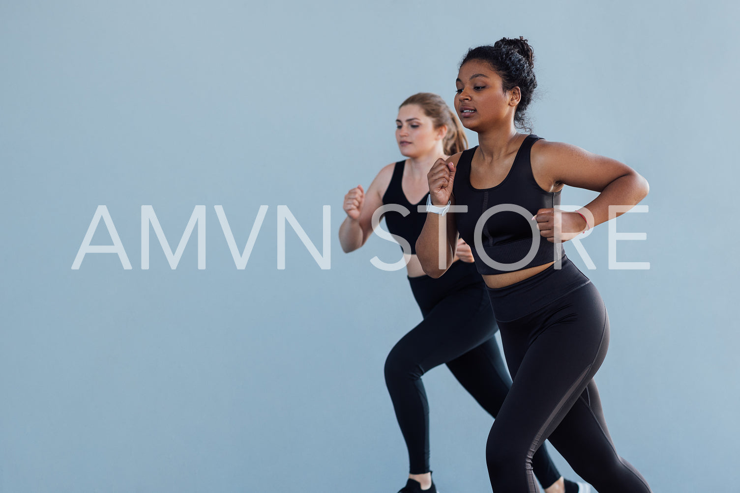 Two females competing each other while running outdoors. Young women jogging outdoors wearing black sportswear.