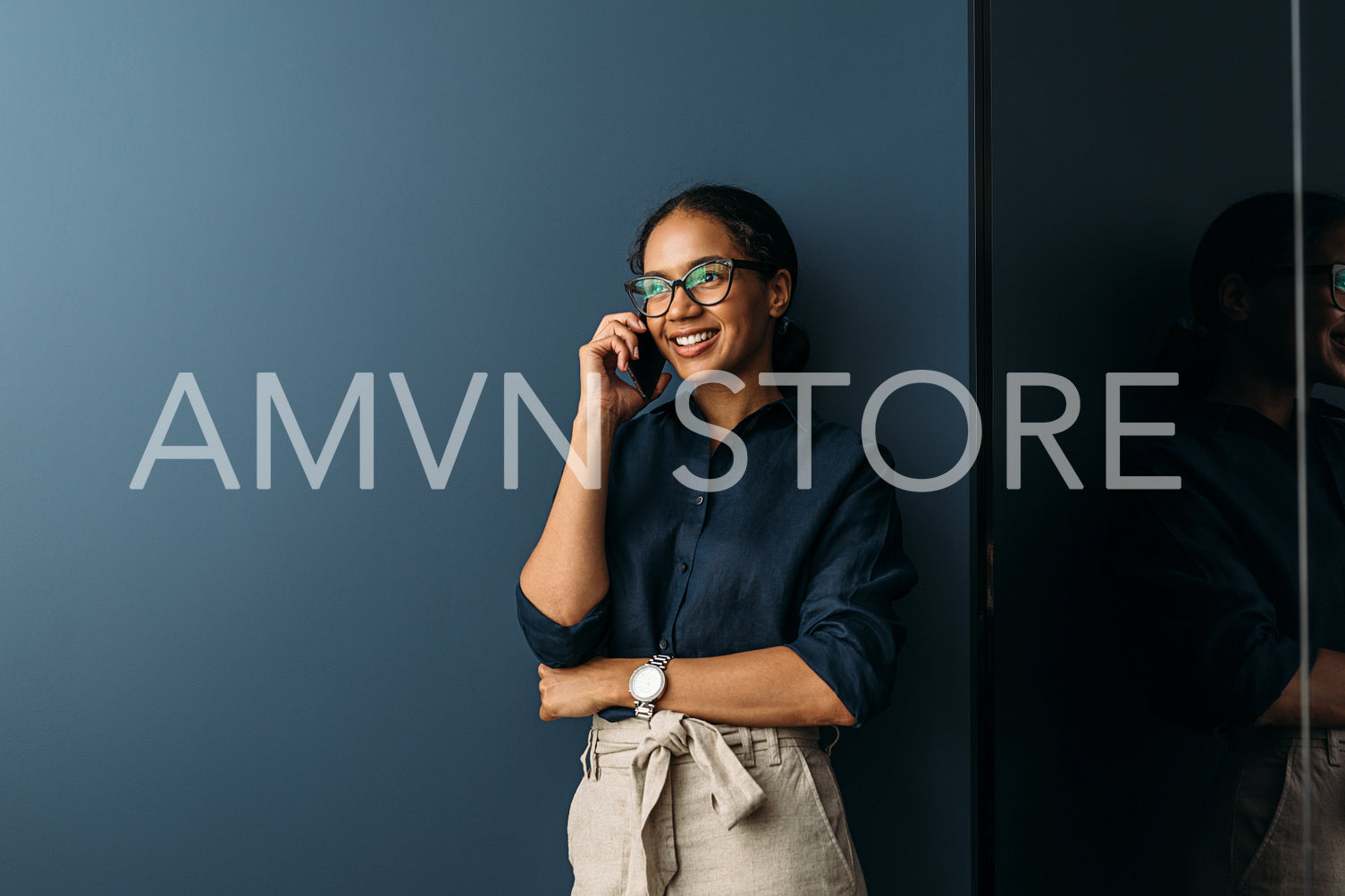 Beautiful smiling businesswoman standing at wall in the living room and talking on cell phone	