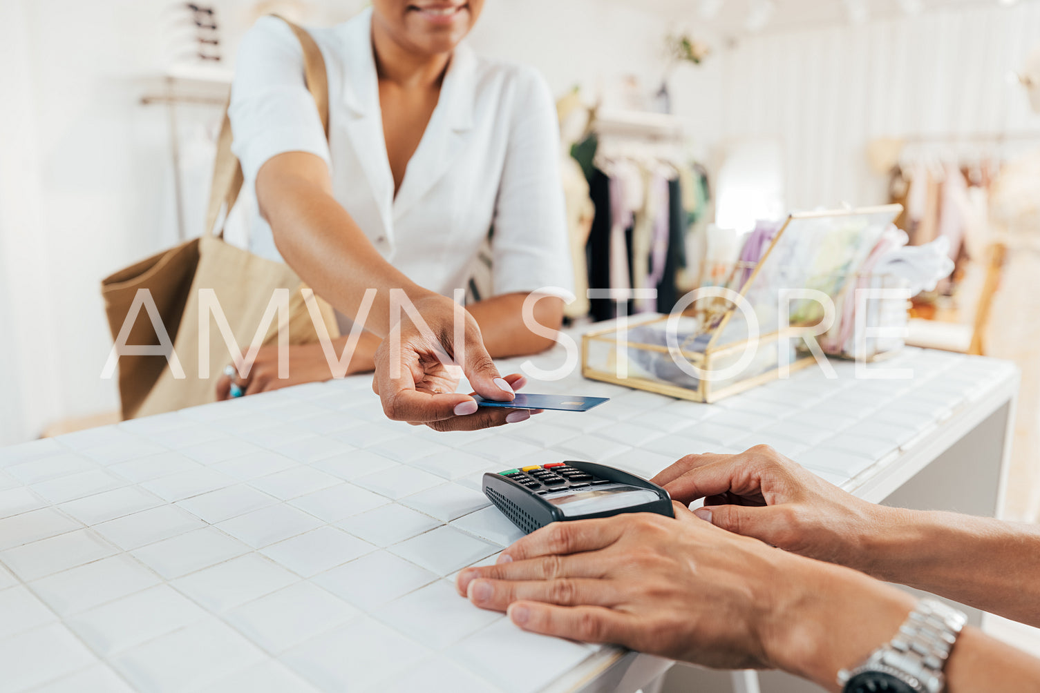 Cropped shot of hands of saleswoman holding pos terminal while female customer paying through credit card