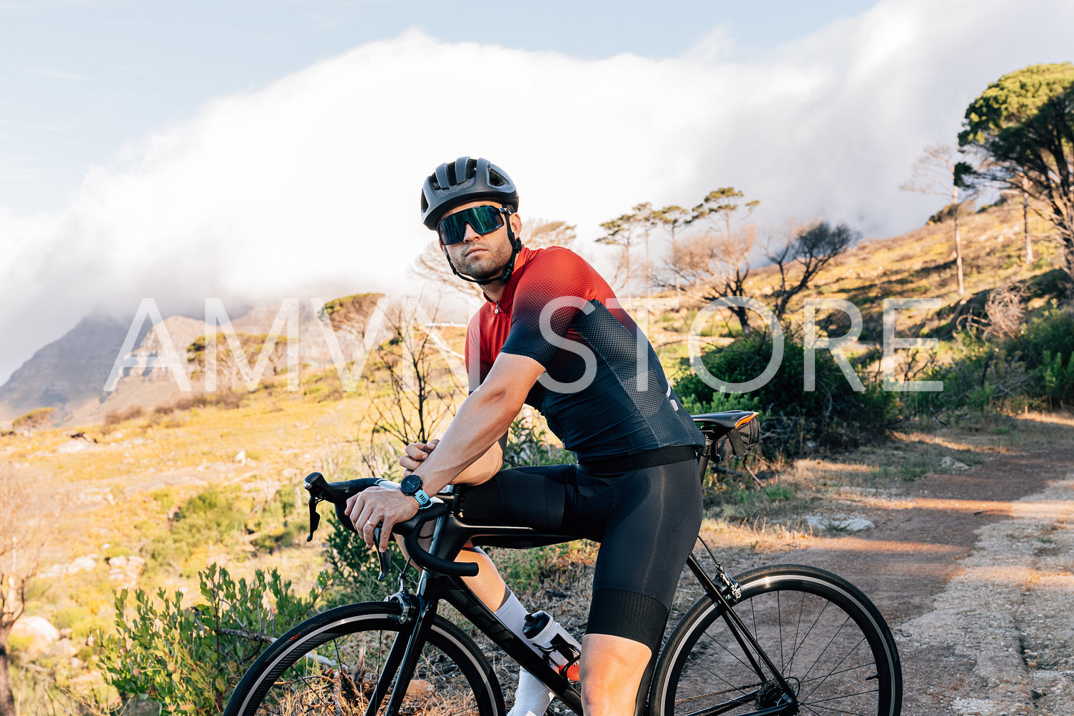 Portrait of a professional cyclist in helmet and glasses standing with bicycle against wild terrain.