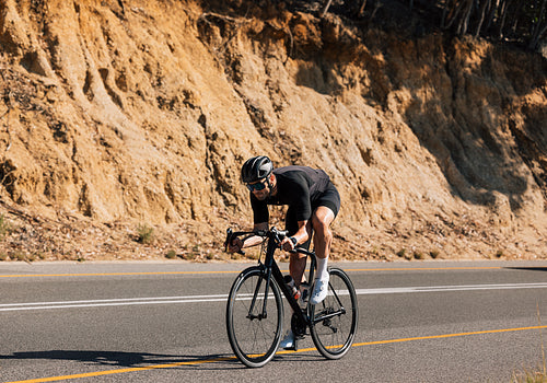 Professional road bike rider practicing on an empty road. Cyclist in a helmet and glasses on a bicycle.